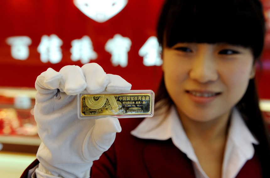 A staff worker shows off the gold bar for the Chinese year of the Snake in a Tianjin jewellery store on Nov. 4. This so-called Chinese zodiac gold bar debuts in the city and comes in five weight categories: 50g, 100g, 200g, 500g and 1,000g. [Xinhua photo]