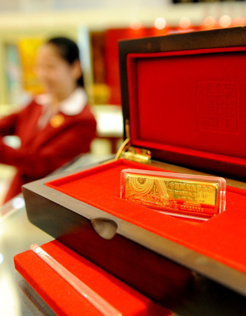 A staff worker shows off the gold bar for the Chinese year of the Snake in a Tianjin jewellery store on Nov. 4. This so-called Chinese zodiac gold bar debuts in the city and comes in five weight categories: 50g, 100g, 200g, 500g and 1,000g. [Xinhua photo]