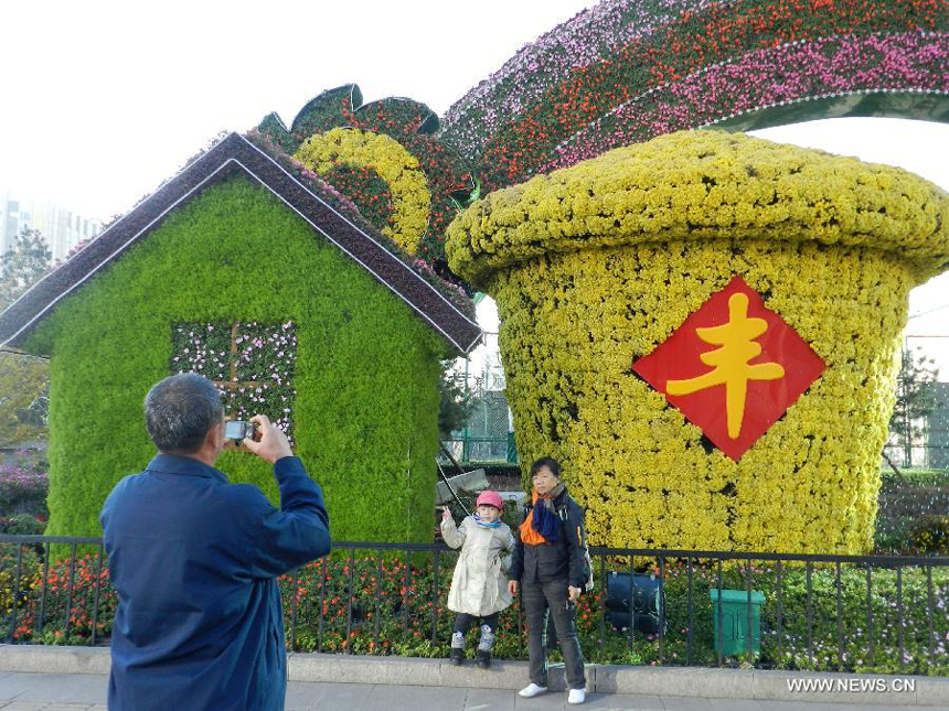 Visitors pose for photos in front of the flower decorations displayed on the street to greet the upcoming 18th National Congress of the Communist Party of China (CPC) in Beijing, capital of China, Oct. 30, 2012. The CPC&apos;s 18th National Congress will be convened on Nov. 8, with more than 2,000 CPC delegates gathering for the meeting, which occurs every five years. A new CPC leadership will be elected during the meeting, setting a new direction for the country&apos;s development in the near future.