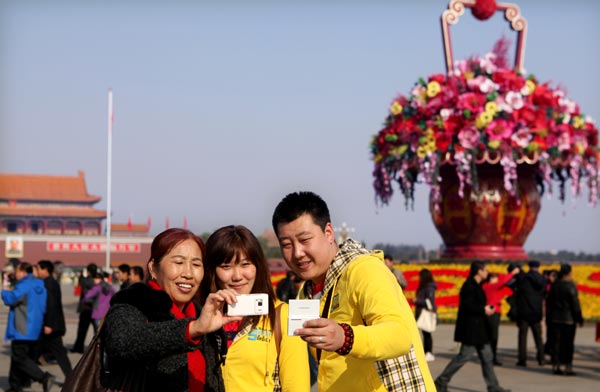 A family of three on Tuesday takes a photo at Beijing’s Tian’anmen Square, which has been decorated with flowers for the upcoming 18th National Congress of the Communist Party of China. [Photo / China Daily]
