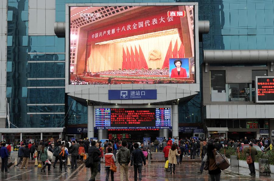 11月8日，旅客们在贵阳火车站站前广场上通过大屏幕观看十八大开幕会直播。当日，中国共产党第十八次全国代表大会在北京隆重开幕。[新华社]