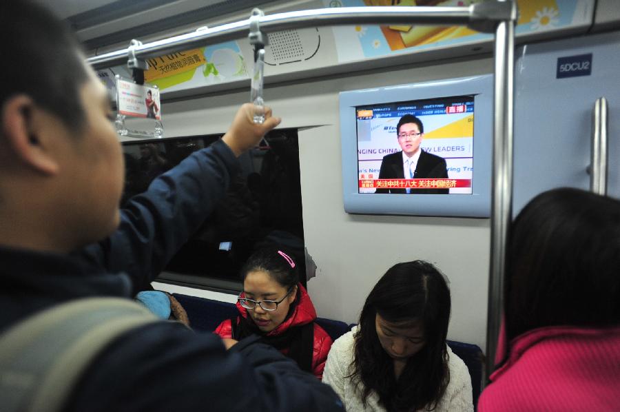 11月8日，在北京地铁二号线列车车厢，市民通过地铁电视关注党的十八大召开。当日，中国共产党第十八次全国代表大会在北京隆重开幕。[新华社]