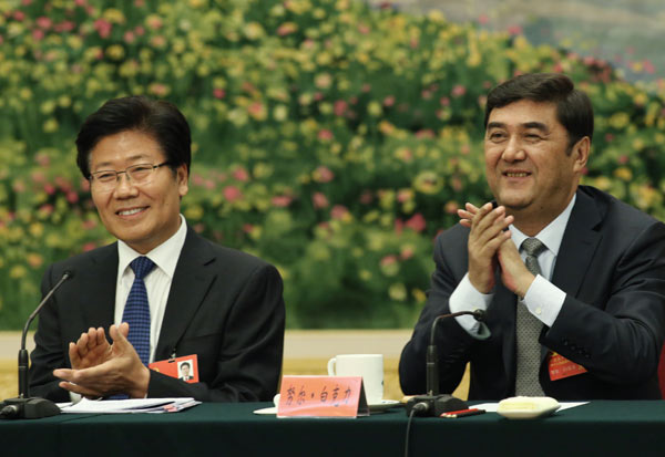 Nur Bekri, right, chairman of the Xinjiang Uygur autonomous region, and Zhang CHunxian, Party chief of Xinjiang, applaud during a session of the ongoing 18th Party Congress in Beijing on Friday. [Photo/China Daily]