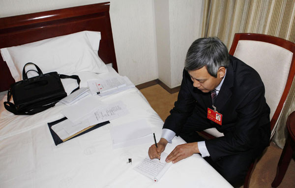 The delegate for migrant workers, Meng Guangbin, writes down his feelings after reading the Congress's report during a break at noon on Nov 10, 2012. 