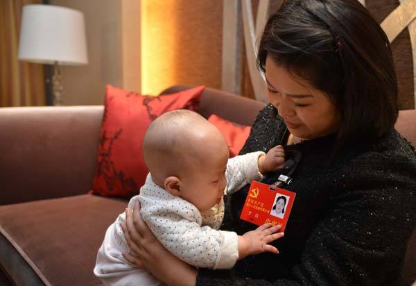 Luo Wei, a deputy to the 18th National Congress of the Communist Party of China, takes care of her five-month-old daughter at a hotel after finishing a group discussion in Beijing on Nov 10, 2012. 