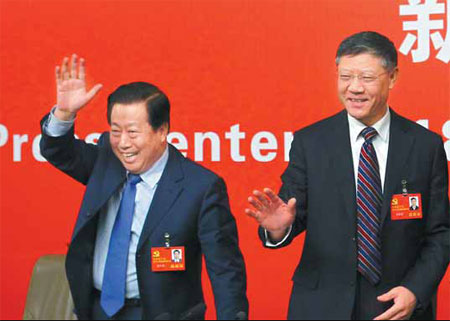 Jiang Weixin (right), minister of housing and urban-rural development, and Zhou Shengxian, minister of environmental protection, wave to reporters at a news conference during the Party congress in Beijing on Monday. [Photo/China Daily]