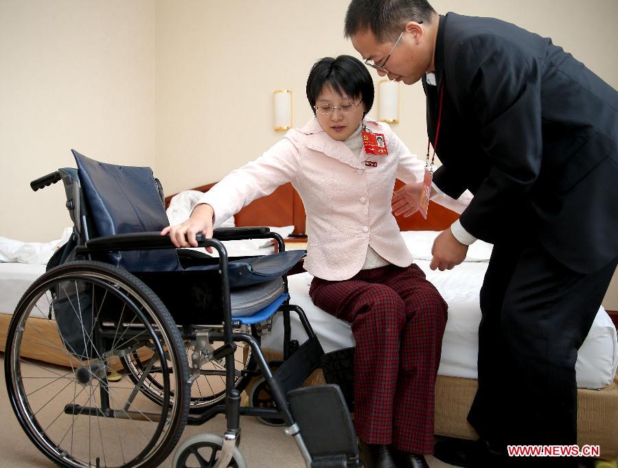 侯晶晶在丈夫相华利的帮助下坐上轮椅。