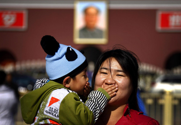A young boy covers the mouth of his mother as they pose for a photograph in front of the portrait of former Chinese Chairman Mao Zedong on Beijing's Tiananmen Square November 12, 2012. [Photo/Agencies]