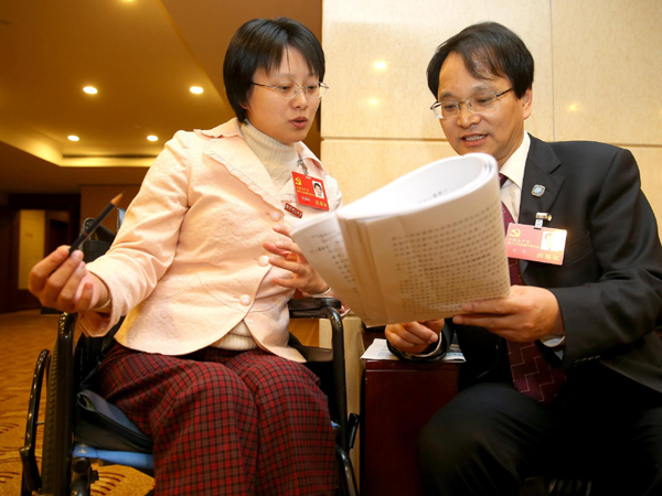 Hou Jingjing holds a discussion with Wang Sheng, a fellow delegate from Jiangsu province, Nov 11.[Photo/Xinhua]
