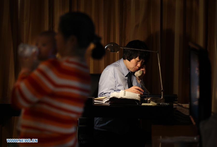 Jiang Min, a delegate to the 18th National Congress of the Communist Party of China (CPC), takes a call at her hotel room while a nanny helps her to take care of the baby in Beijing, capital of China, Nov. 13, 2012. 