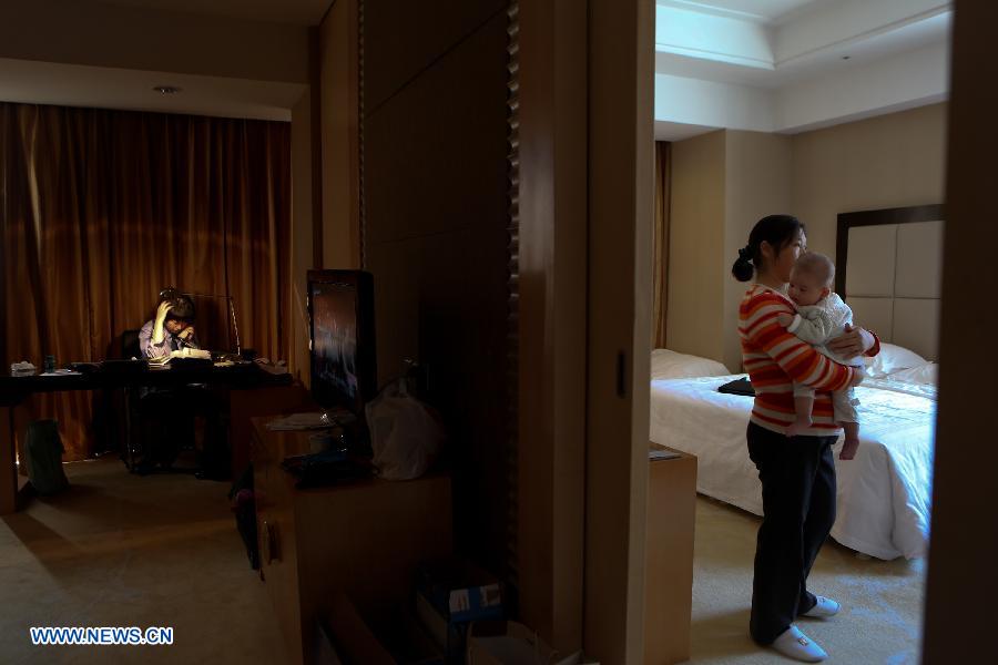 Jiang Min, a delegate to the 18th National Congress of the Communist Party of China (CPC), takes a call at her hotel room while a nanny helps her to take care of the baby in Beijing, capital of China, Nov. 13, 2012.