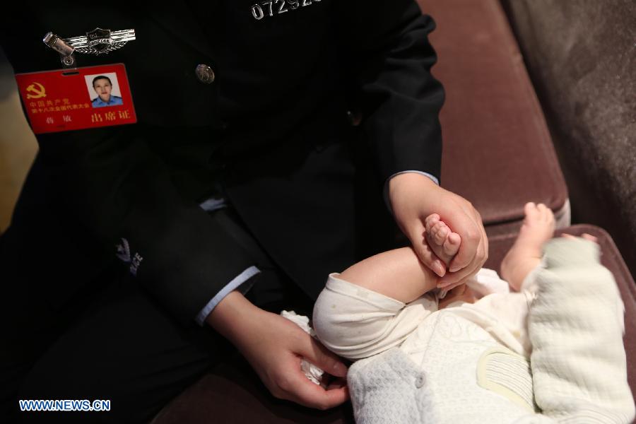 Jiang Min, a delegate to the 18th National Congress of the Communist Party of China (CPC), takes care of her son in Beijing, capital of China, Nov. 13, 2012.