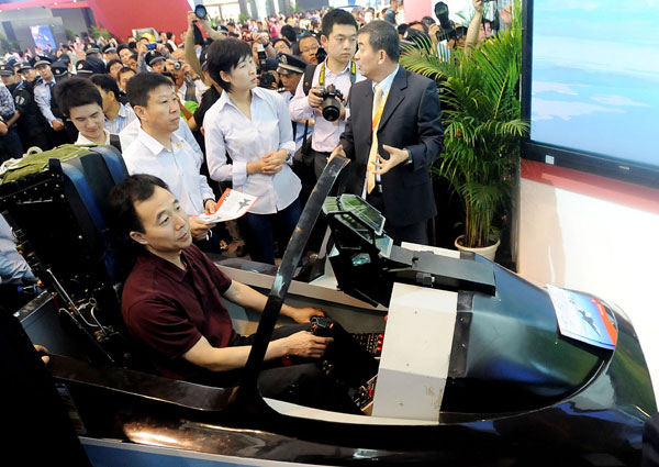 Astronauts Jing Haipeng (in the aviation simulator), Liu Wang (second left, second row) and Liu Yang (central, second row) try the aviation simulator of the Lieying L15 advanced trainer at the Ninth China International Aviation and Aerospace Exhibition in Zhuhai, Guangdong province, on Wednesday.[Photo/China Daily]