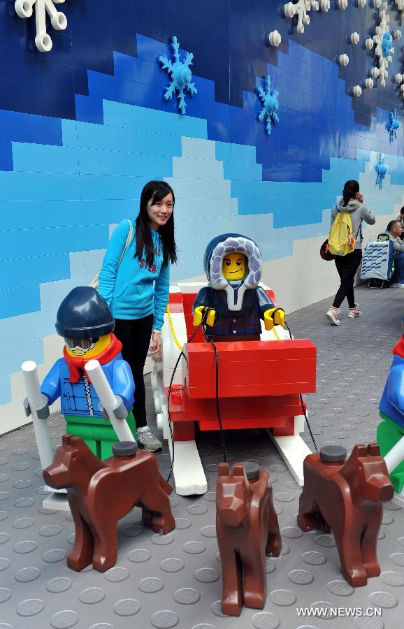 A woman poses for pictures with a sledge built with building blocks at the Times Square in Causeway Bay in south China's Hong Kong, Nov. 16, 2012. As Christmas is drawing near, decorations have been used for creating atmosphere in Hong Kong.