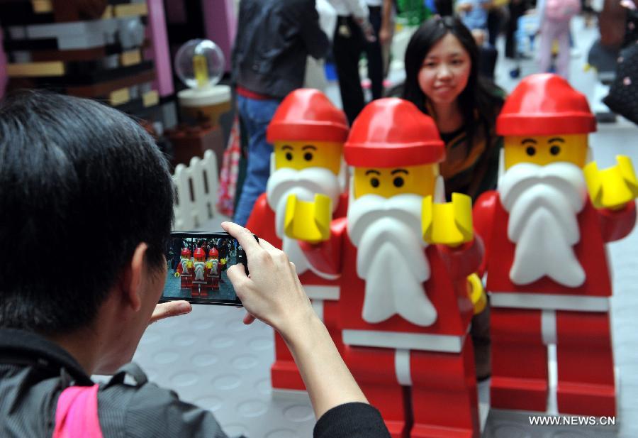 A woman poses for pictures with a sledge built with building blocks at the Times Square in Causeway Bay in south China's Hong Kong, Nov. 16, 2012. As Christmas is drawing near, decorations have been used for creating atmosphere in Hong Kong. 