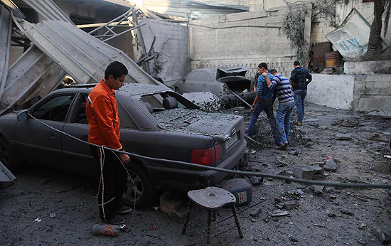 A Palestinian looks at a damaged vehicle parked outside the branch of the Islamic National Bank after a airstrike by Israel, in Gaza City, on Nov. 20, 2012. On the seventh day of Israel's aerial offensive here, the death toll has reached 114, with more than 800 people wounded, according to the Health Ministry. [Xinhua Photo]