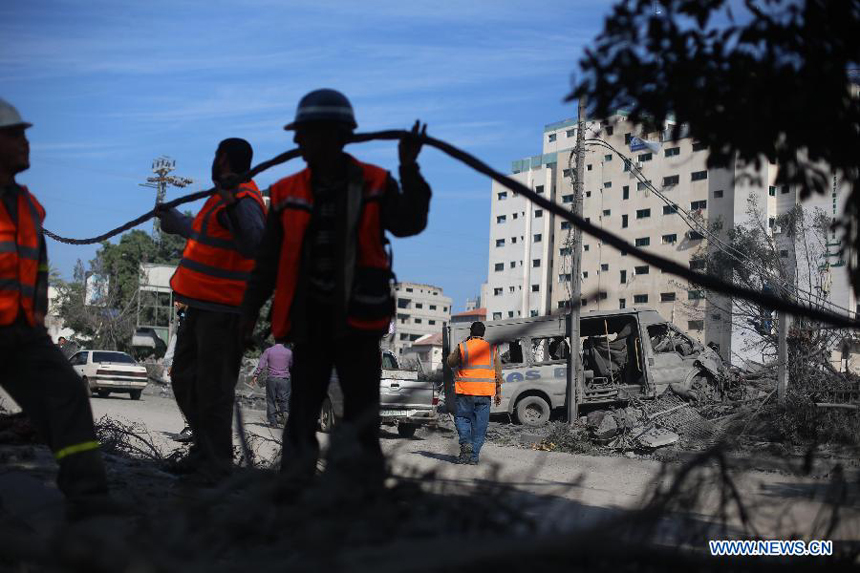 Palestinian electricity workers fix power cords at the destroyed compound of the internal security ministry in Gaza City after it was targeted by an overnight Israeli air strike on Nov. 21, 2012. 