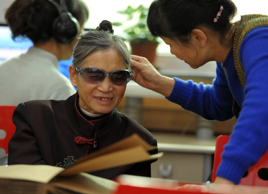 A librarian strokes the hair of Li Fuming, who has no sight, at a reading room for the blind in Gansu Library, Lanzhou, Northwest China&apos;s Gansu province on Nov 21, 2012.