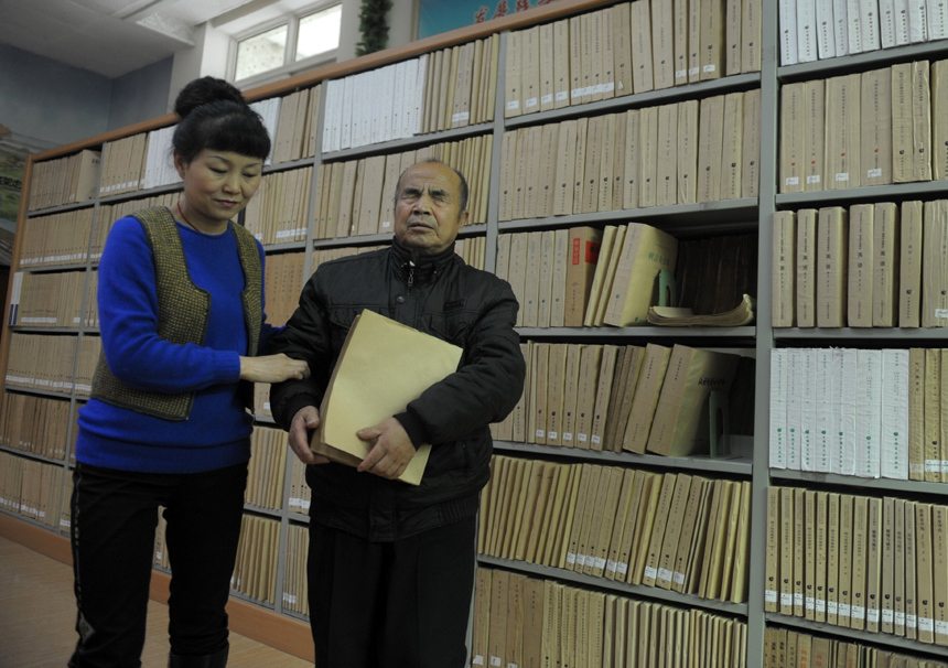 Librarian Wang Jin of Gansu Library helps a blind reader select a Braille book in Lanzhou, Northwest China&apos;s Gansu province on Nov 21, 2012. [Photo/Xinhua]