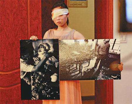 A volunteer depicting a victim of domestic violence shows pictures of abused victims during a lecture against domestic violence in Hangzhou, Zhejiang province, in September. [Photo/China Daily]