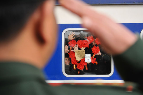 Retired soldiers stick flower paper cuts to a train window as they say goodbye to their comrades in Tianjin on Nov 25, 2012. [Photo/Xinhua]