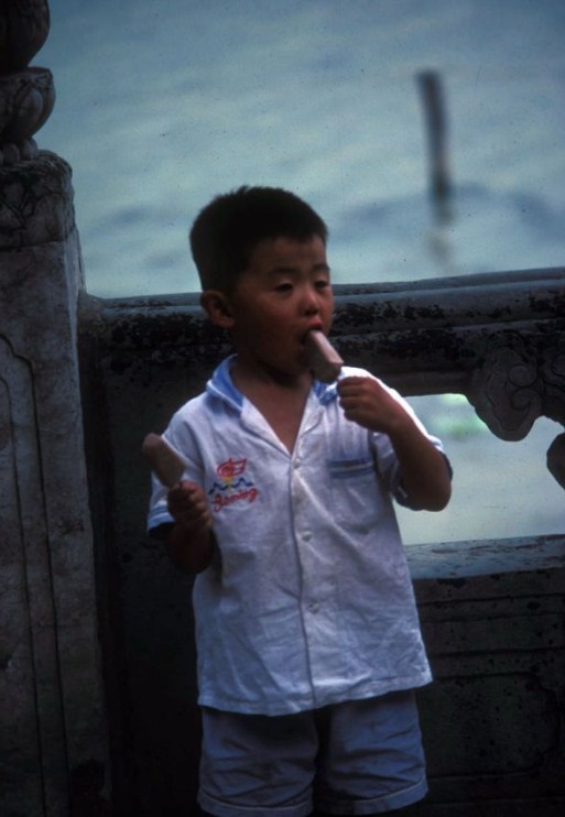 A kid is sucking a three-cent ice-lolly.