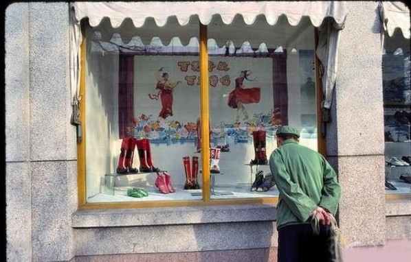 A man is looking at boots in a window display.