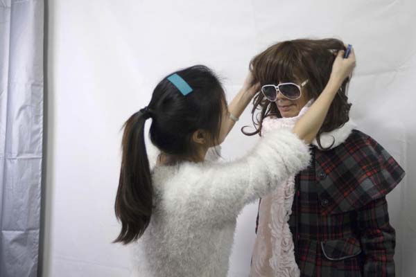 Lu Ting helps put on a wig on 72-year-old Liu Qianping, also known as 'MaDiGaGa', a modelling shoot in the southern Chinese city of Guangzhou Nov 24, 2012. [Photo/China Daily via Agencies]