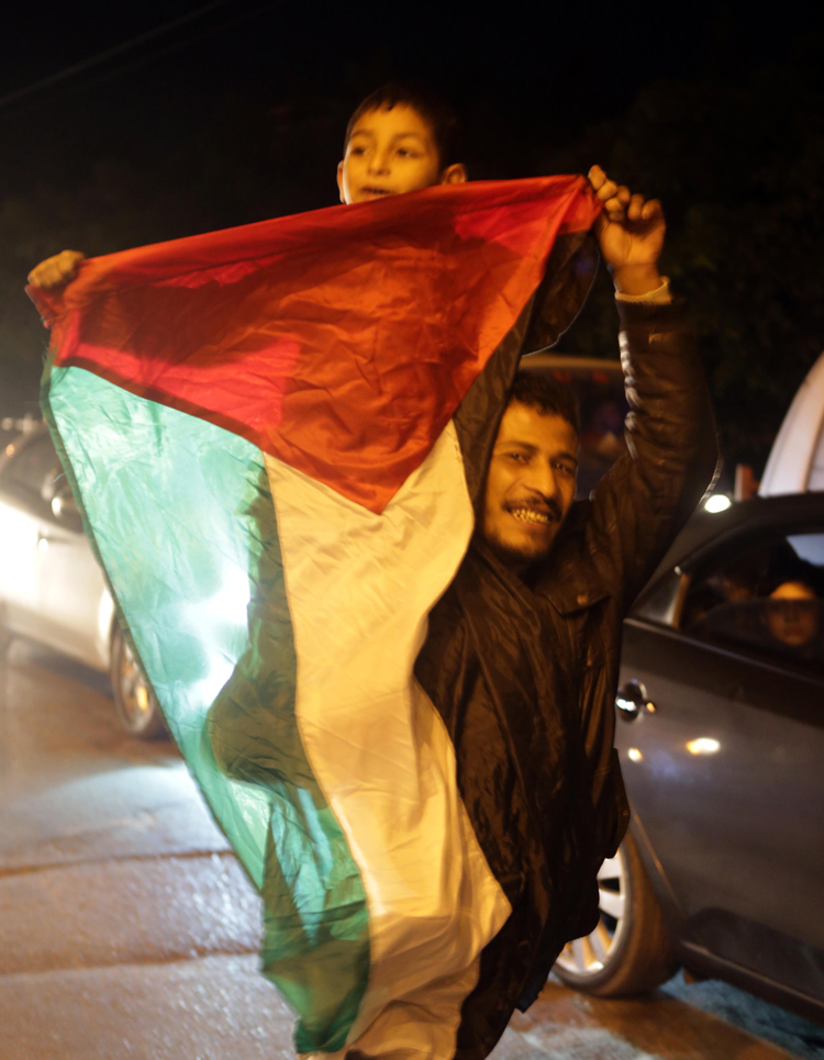 A Palestinian man carrying his son on his shoulders wave his national flag as he celebrates in Gaza City early on November 30, 2012, after the UN General Assembly voted to upgrade them to a non-member state observer. The UN General Assembly on Thursday voted overwhelmingly to recognize Palestine as a non-member state, triggering scenes of joy on the streets of the Israeli-occupied West Bank. In a major defeat for the United States and Israel, Palestinian president Mahmud Abbas won what he called a &apos;birth certificate&apos; for a Palestinian state, with the backing of 138 countries in the 193 member assembly. 