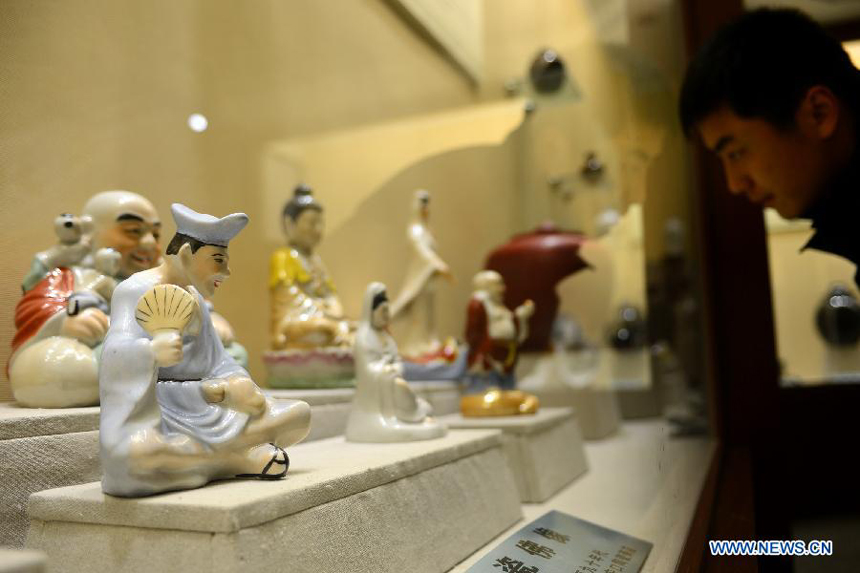 A visitor views the traditional Huating painting ceramics crafts during an exhibition in Huating County, northwest China&apos;s Gansu Province, Nov. 29, 2012. Huating ceramics have a history of thousands of years, producing arts like slip casting and ceramics painting and many varieties with local characteristics. Nowadays, constant technical renovation and grooming of successors to painting ceramics are made to revive the local ceramics painting industry.