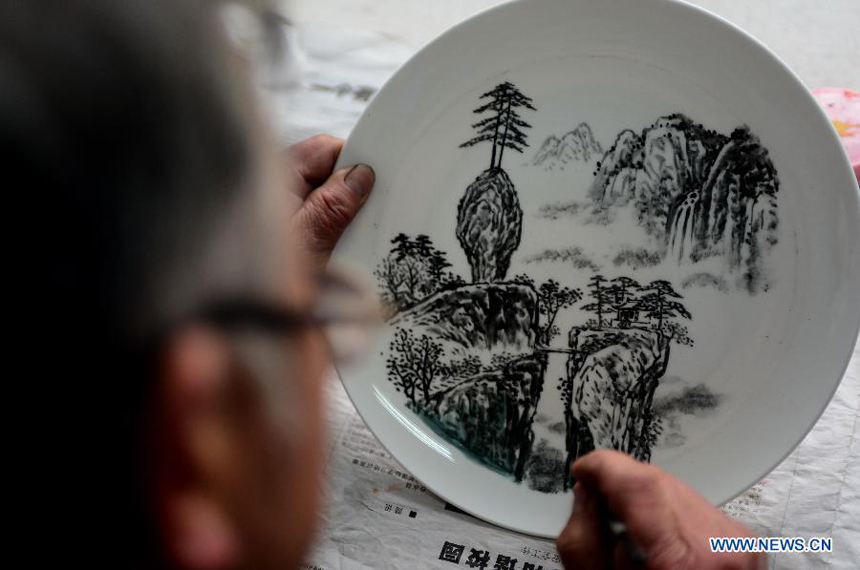 Bian Xiping, inheritor of intangible cultural heritage ceramic arts and crafts, paints on a ceramic plate by using traditional skills in Huating County, northwest China&apos;s Gansu Province, Nov. 29, 2012. Huating ceramics have a history of thousands of years, producing arts like slip casting and ceramics painting and many varieties with local characteristics. Nowadays, constant technical renovation and grooming of successors to painting ceramics are made to revive the local ceramics painting industry. 