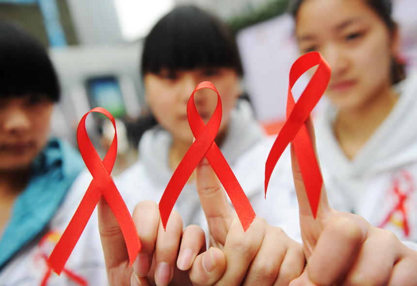 Volunteers from Chongqing show red ribbons on Nov. 30, 2012. The World AIDS Day falls on Dec. 1 and is marked across China. [Photo/Xinhua] 