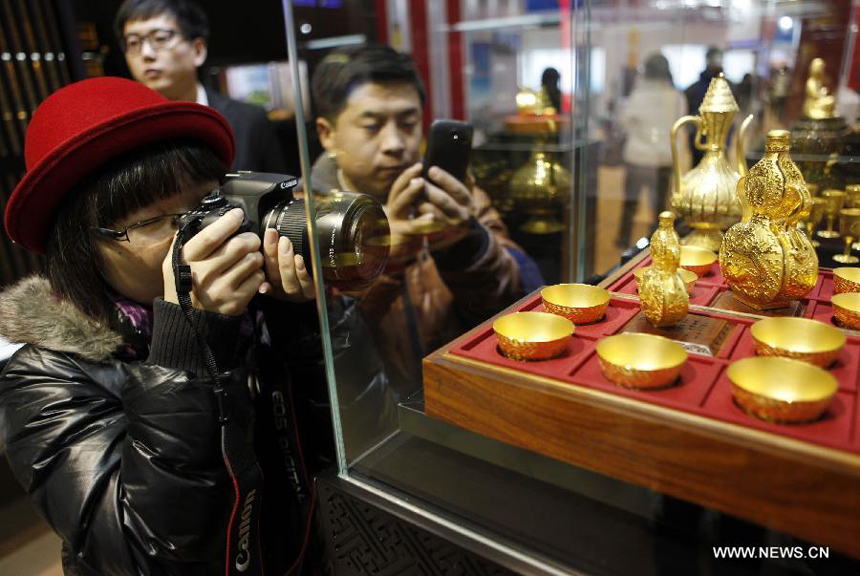 Visitors take photos of a work of art which is made of gold at the 8th Beijing International Finance Conference in Beijing, capital of China, Dec. 3, 2012. The four-day conference was closed on Monday. 