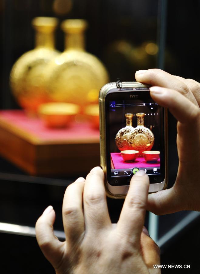 A visitor takes photos of a work of art which is made of gold at the 8th Beijing International Finance Conference in Beijing, capital of China, Dec. 3, 2012. The four-day conference was closed on Monday. 