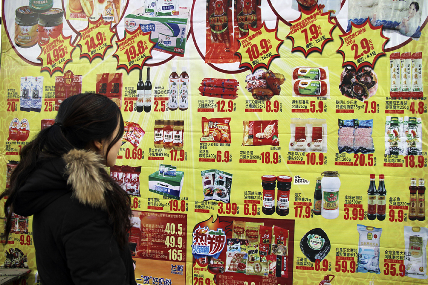 A lady looks at commodity promotion ads at a market in Handan, Hebei Province, Dec. 9, 2012. China&apos;s consumer price index (CPI), a main gauge of inflation, grew 2 percent year on year in November, the National Bureau of Statistics announced Sunday. The inflation rate increased from a 33-month low of 1.7 percent in October as food prices increased. 