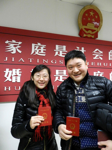 A newly wed couple shows their marriage certificate at a registration office in Beijing on Dec 12, 2012. [Photo/Xinhua]