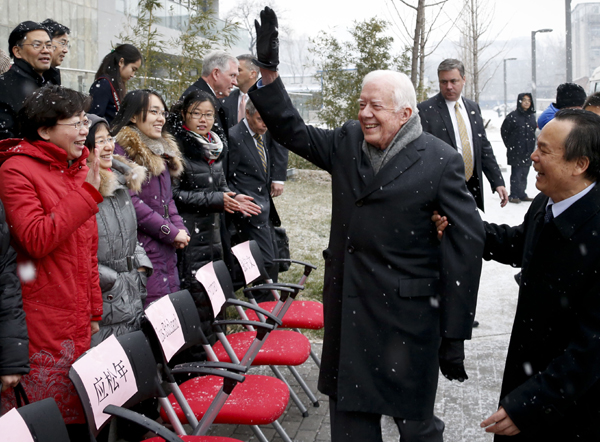 Former United States president Jimmy Carter waves to a group of people before taking a picture with them in Beijing on Wednesday. Carter visited Peking University on Wednesday and made a speech at a seminar organized by the university and The Carter Center. [Photo/China Daily]