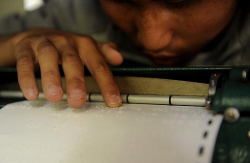  A student reads Tibetan Braille. [Xinhua]