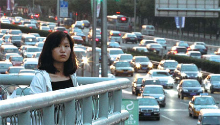 A woman stands on a pedestrian bridge overlooking the Fourth Ring Road in northeast Beijing during rush hour in September. [China Daily]