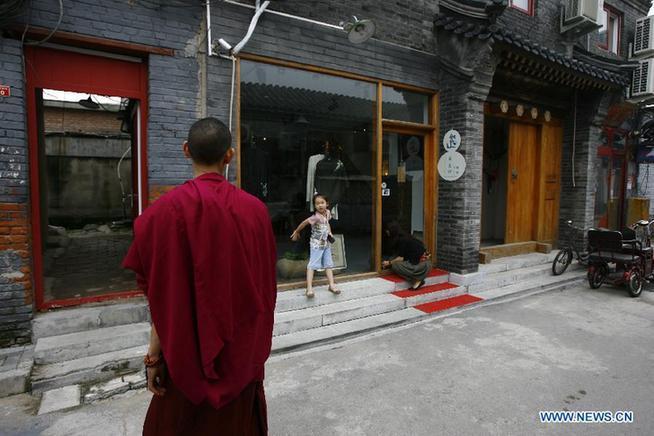 A little girl greets her Lama friend in front of her family's clothing shop in Wudaoying Hutong in Beijing, China, Aug. 30, 2011. This is one of Beijing's oldest Hutongs, yet it is also the city's newest trendy hangout.