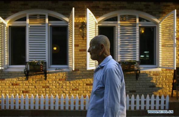 An aged Chinese man walks by a western restaurant in Wudaoying Hutong in Beijing, China, Sept. 24, 2011.