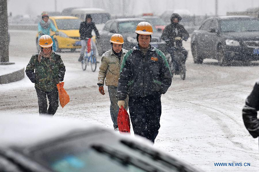 Workers walk on Changfeng Road in Taiyuan, capital of north China&apos;s Shanxi Province, Dec. 20, 2012. Many parts in Shanxi saw heavy snowfall on Thursday. 