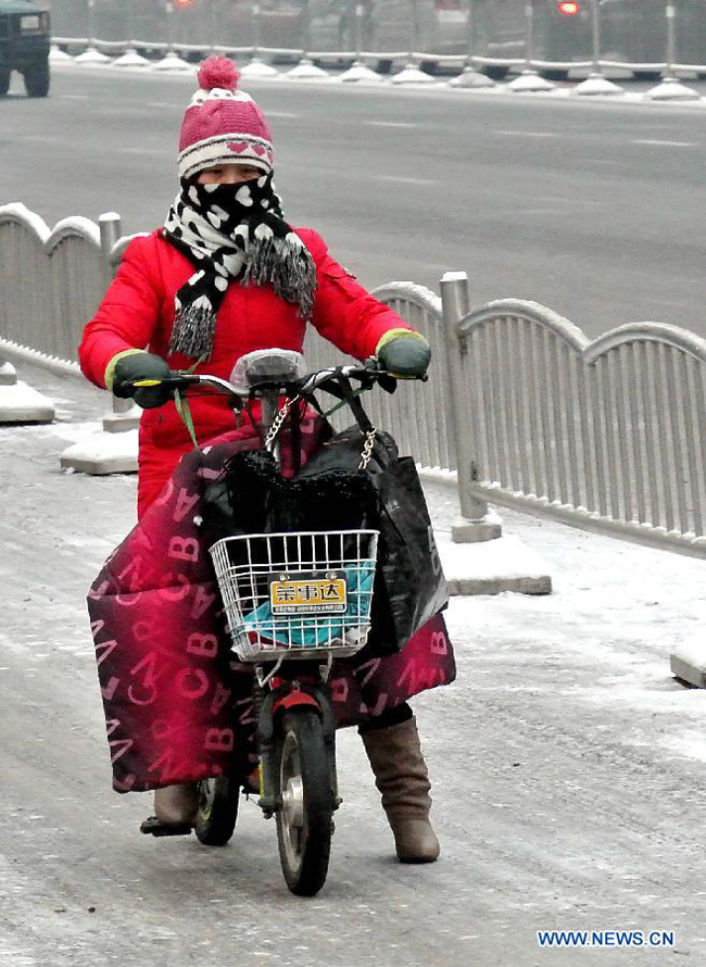 A citizen rides on a frozen street in Zhengzhou, capital of central China's Henan Province, Dec. 21, 2012. A snow hit most parts of Henan since Thursday night. 