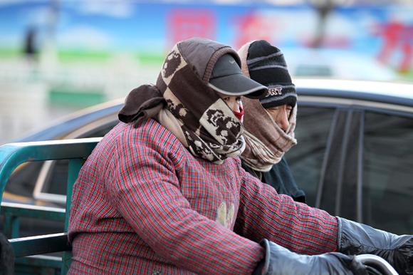 People brave the cold in Qinhuangdao, Hebei Province, on Dec. 23, 2012. A cold front has descended on many provinces, with temperatures in some cases hitting well below -20 C.