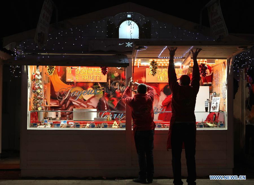  Two men close their shop at the Christmas market on the Champs-Elysees avenue in Paris, France, Dec. 23, 2012.
