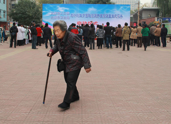 An elderly woman walks through a square during a launch ceremony for a health service for married couples whose only child has died in Taiyuan, Shanxi province, in October. The couples receive medical services from local family planning and health authorities. [Photo/China Daily]