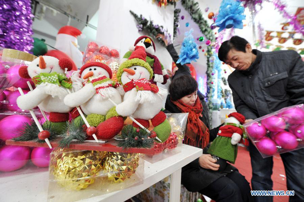 A staff member (R) recommends Christmas ornaments to a customer at a holiday decoration store in Yinchuan, capital of northwest China&apos;s Ningxia Hui Autonomous Region, Dec. 19, 2012. As Christmas is drawing near, shopping malls and decoration stores in Yinchuan start to sell related decoration articles.