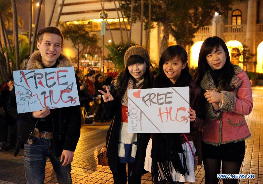 Citizens pose for photos with signs reading &apos;free hug&apos; at the Statue Square in Hong Kong, south China, on Dec. 24, 2012.