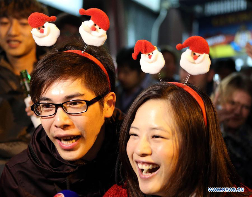 Two visitors with Christmas headwears are interviewed at Lan Kwai Fong, a commercial area in Hong Kong, south China, early Dec. 25, 2012. 