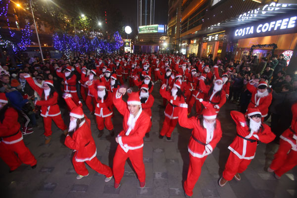 One hundred Santas dance in Wuhan, Central China's Hubei province on Christmas eve on Dec 24, 2012. [Photo/Asianewsphoto]
